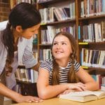 Female teacher and little girl in library