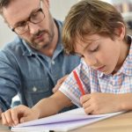 Teacher helping schoolboy with wRiting lesson